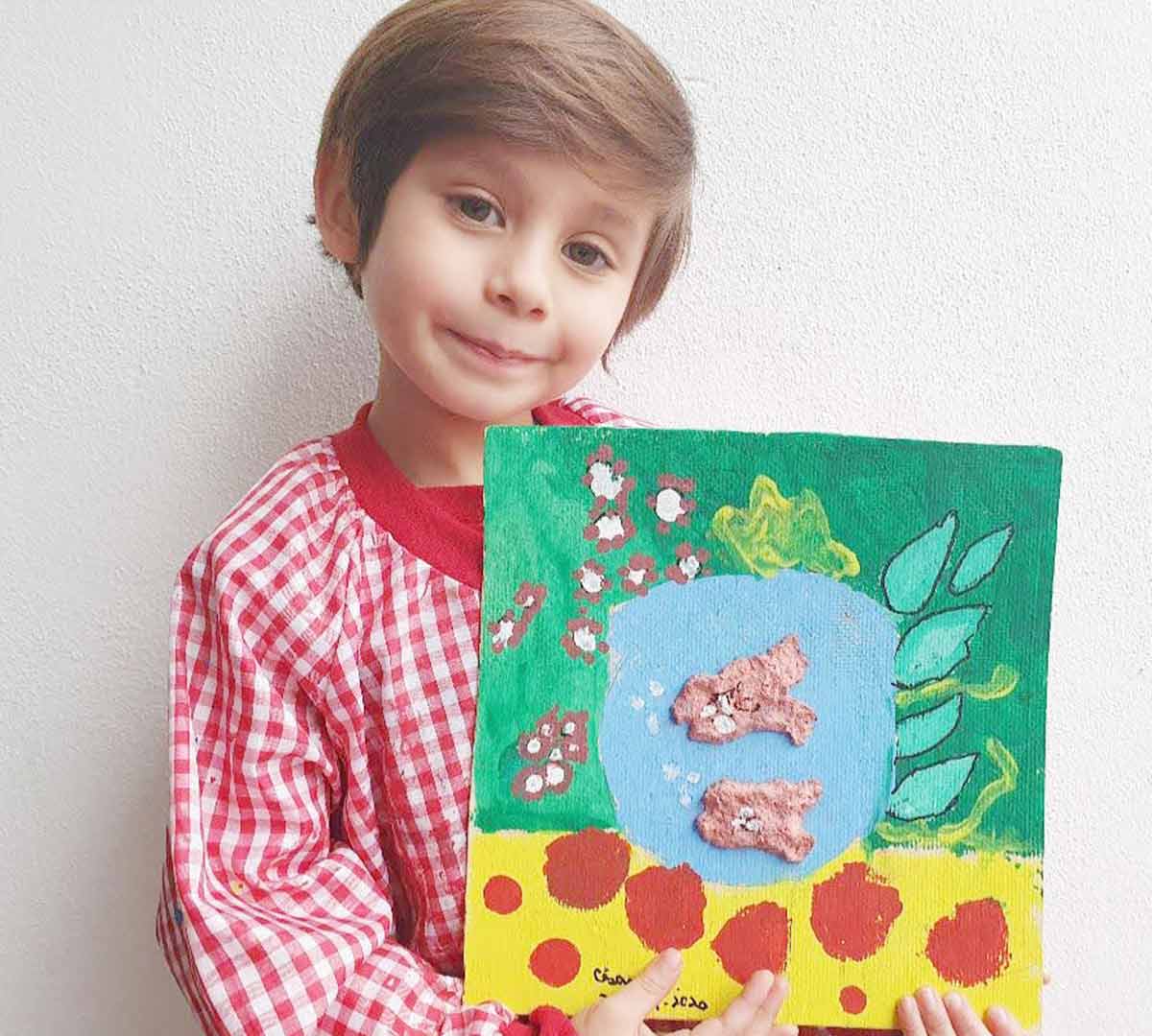 Alumno de primaria muestra en sus manos pintura hecha por él mismo.